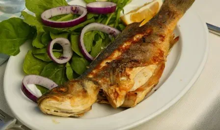 Izgara levrek, roka ve mor soğanla beyaz tabakta