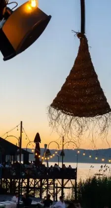 Gün batımında hasır abajur, iskelede ışık zinciri
